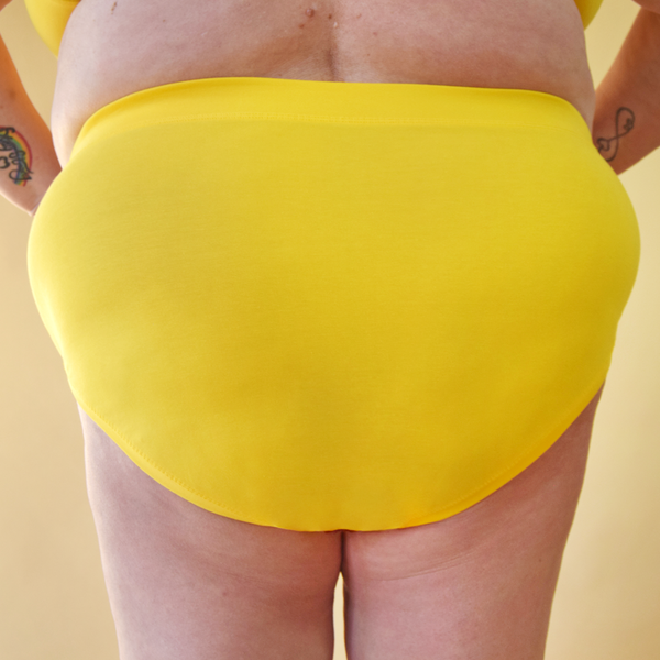 Cropped image of Julie wearing marigold yellow high rise briefs