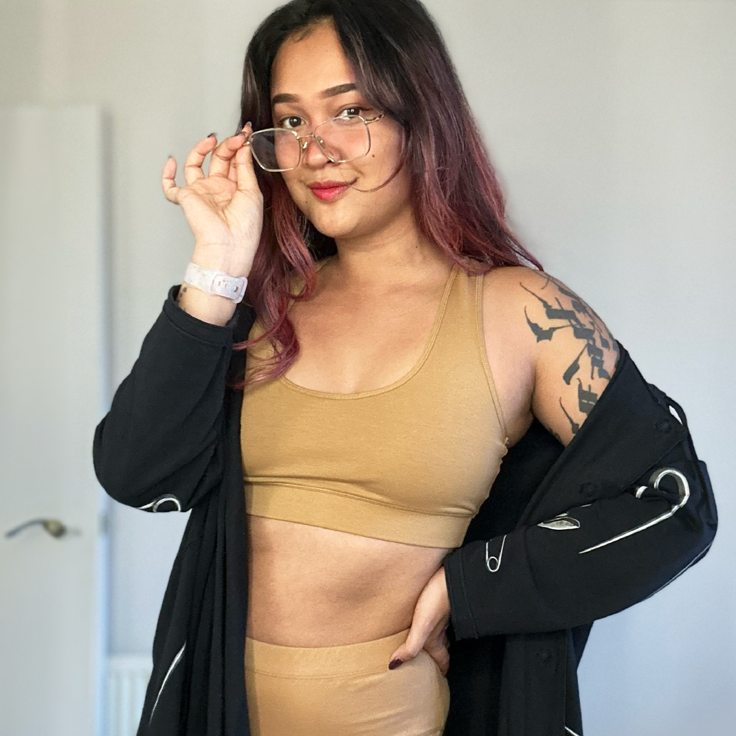 Sarah is wearing a Nude racerback bralette and briefs under a black zip up top