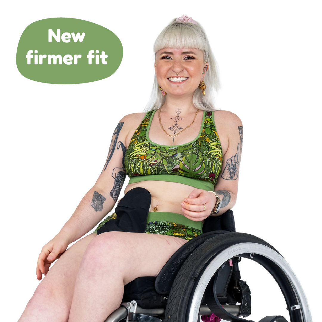 Jess is sitting in her wheelchair smiling wearing a Botany racerback bralette and briefs. 'New firmer fit' is in the top left corner