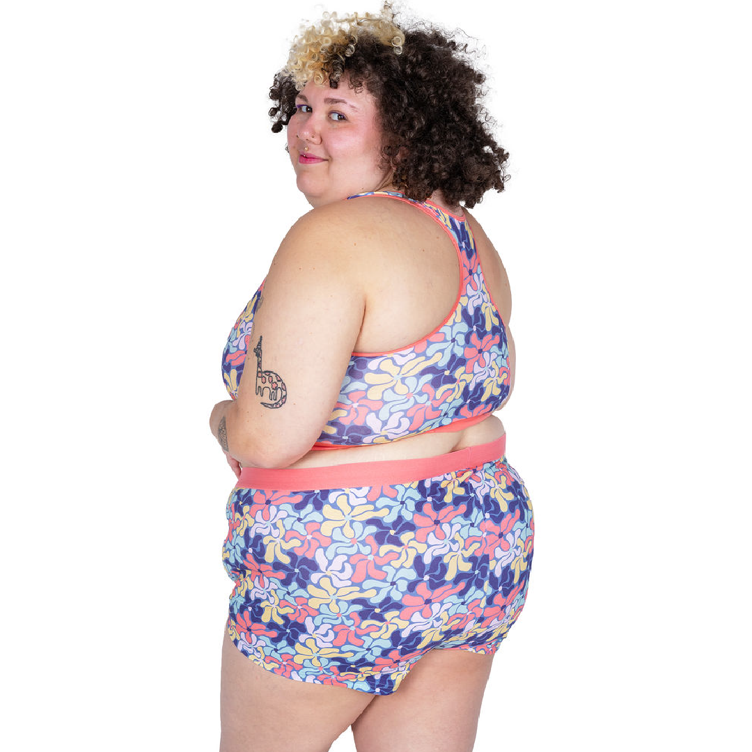Sofaya looking over her shoulder wearing a racerback bralette and boxer briefs in wavy flowers