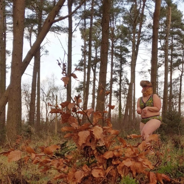 Model in dinosaur mask and underwear in the woods