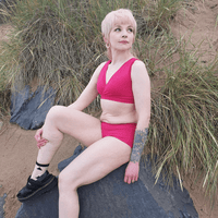 Sophia is wearing a raspberry pink underwear set sitting on a rock