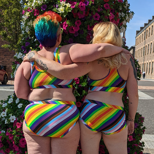 Back view of Kirsty and Eilidh. Kirsty is wearing high rise rainbow briefs and bra and Eilidh has mid rise briefs and bralette